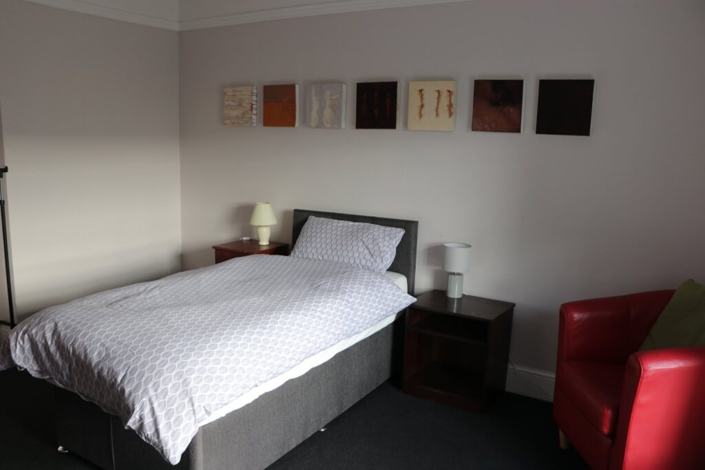 Bedroom with a double bed and red armchair in Newtown House